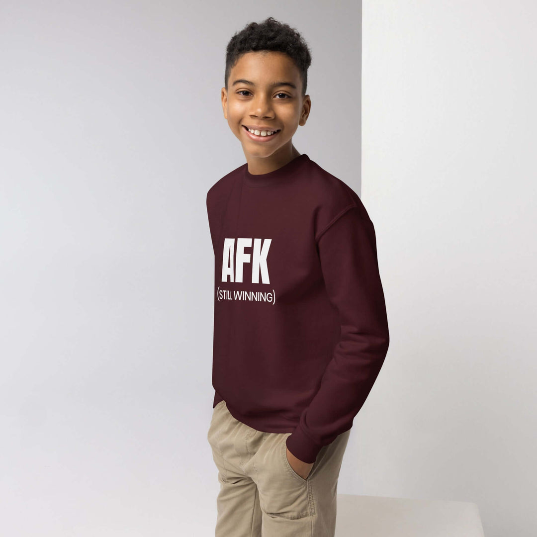 AFK Youth crewneck sweatshirt worn by a smiling boy in a burgundy color, showcasing a cool design perfect for adventures.