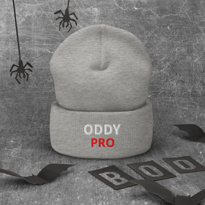 Oddy Pro Cuffed Beanie displayed on a textured background with Halloween decorations.